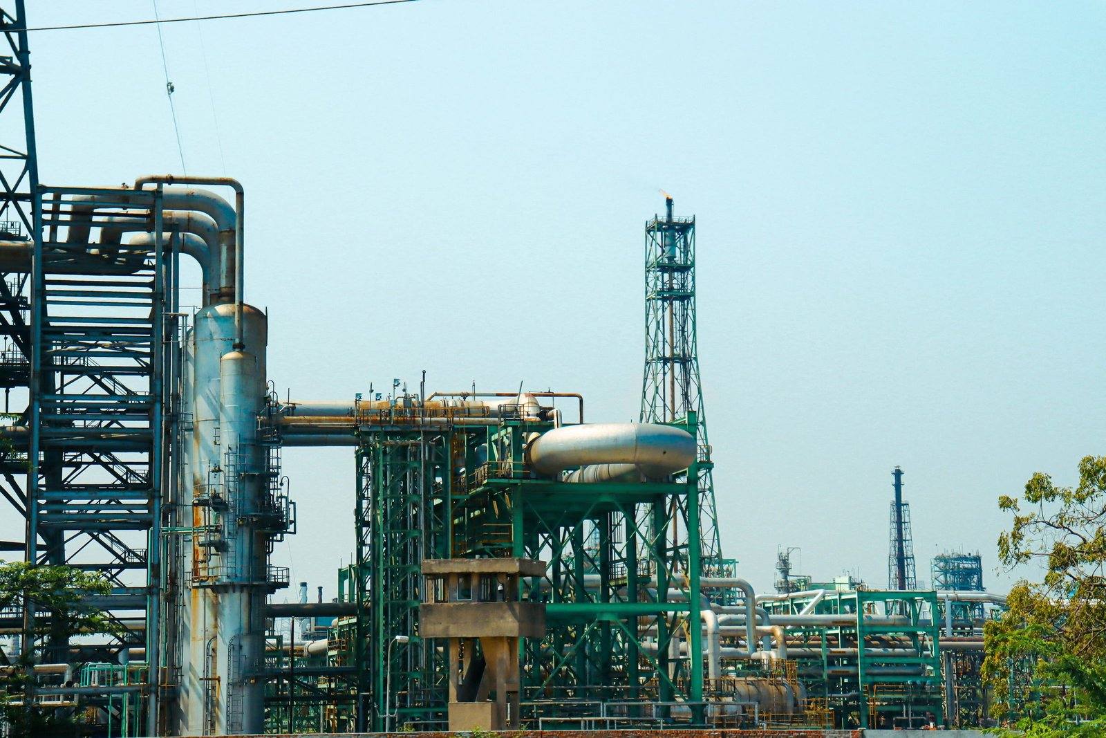 An industrial process plant with pipe racks and a flare stack against an open sky