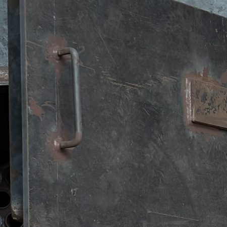 Close-up of a welded structural joint and access door hardware